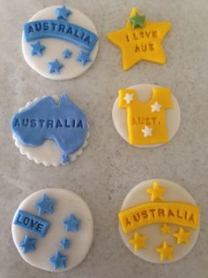 four decorated cookies with the names of australia and i love australia in blue, yellow and white