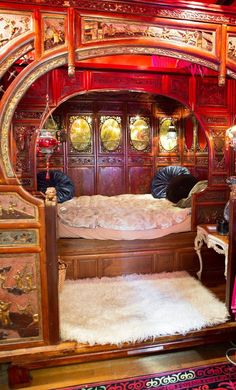 an elaborately decorated bed in the middle of a room with red walls and wood trimming