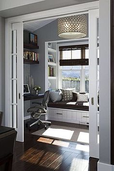 an open door leading to a living room with a window seat and bookshelf