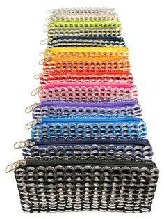 many different colored zippers are lined up in the shape of a basket with metal handles