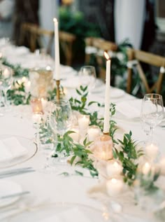 the table is set with candles and greenery