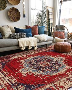 a living room filled with lots of furniture and pillows on top of a red rug