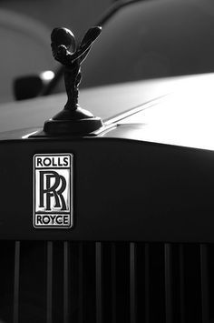 a rolls royce emblem on the hood of a black car with blue sky in the background