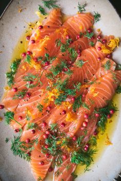 some salmon is on a white plate and garnished with green sprigs