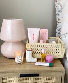 a nightstand with various items on it and a pink lamp next to the dresser top