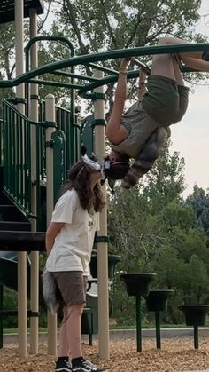 a woman is hanging upside down on a playground