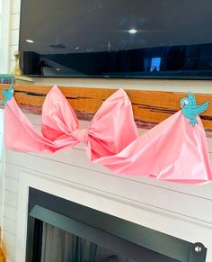 two pink bows are sitting on top of a fireplace