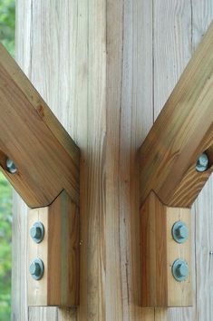 two wooden brackets are attached to the side of a wood structure with metal rivets