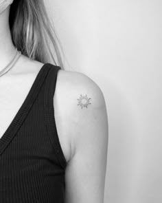 a black and white photo of a woman with a small sun tattoo on her left shoulder