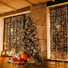 a decorated christmas tree in front of two windows with lite up lights on them