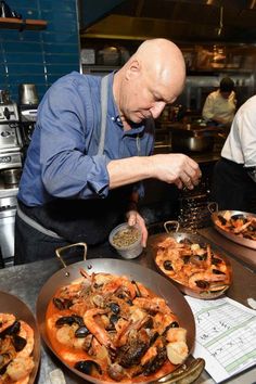 a man standing in front of two pans filled with food on top of a counter