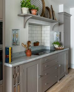 a kitchen with gray cabinets and white tile backsplashes, pots and pans on the shelves