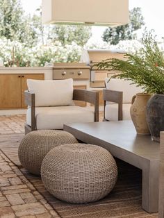 an outdoor living area with furniture and potted plants on the coffee table in front of it