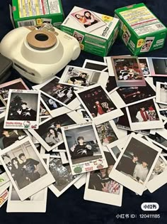 a pile of polaroid pictures sitting on top of a table next to a camera