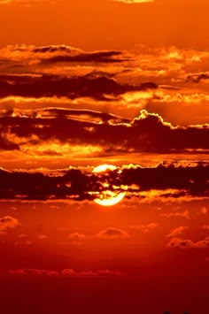 the sun is setting behind some clouds in the sky with an airplane flying below it