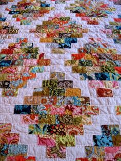 a colorful quilt is laying on top of a bed