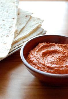 a bowl of salsa next to tortillas on a table