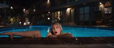 a woman laying on the ground in front of a pool at night with her legs spread out