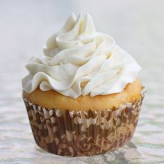 a cupcake with white frosting sitting on top of a table