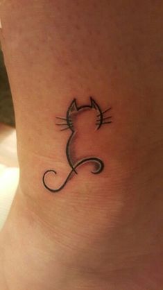 a small cat tattoo on the side of a woman's ankle, with black ink