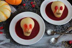 two white plates topped with desserts covered in icing and sugar skull heads next to pumpkins