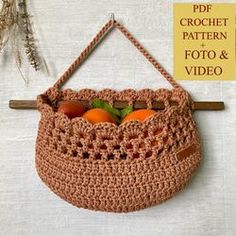 a crocheted purse hanging on a wall with an orange in the bottom half