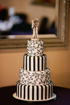 a three tiered cake with black and white stripes on it is displayed in front of a mirror