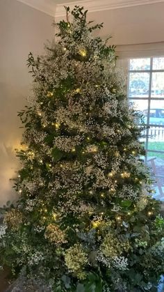 a white christmas tree with lights and greenery