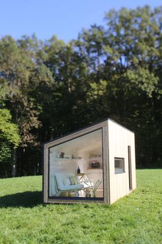 a small house sitting on top of a lush green field with trees in the background