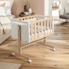 a baby crib sitting on top of a hard wood floor next to a bed