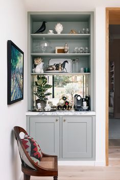 a chair sitting in front of a book shelf filled with lots of books and knick knacks