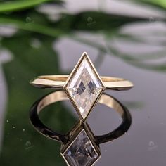 a diamond ring sitting on top of a green leafy surface with water in the background