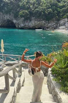 a woman is walking down some stairs near the water