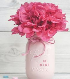 a mason jar with pink flowers in it on top of a table next to crayons