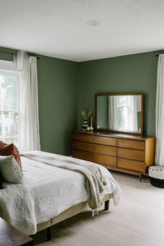 a bedroom with green walls and white curtains