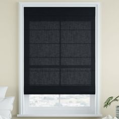 a bedroom with a window covered in black roman shades