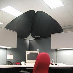 an office cubicle with a red chair and computer monitor on the desk in front of it