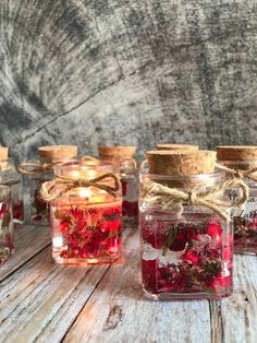 several jars filled with different types of flowers and herbs sitting on a wooden table next to each other