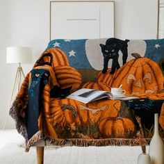 a cat sitting on top of a pumpkin covered couch