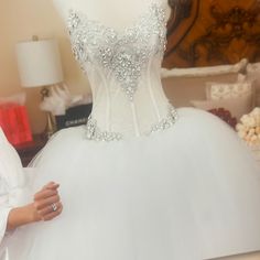 a woman standing next to a white dress on a mannequin display in a store