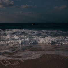 the waves are crashing on the beach at night