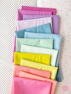 several different colors of fabric laid out on top of each other in front of a polka dot wall