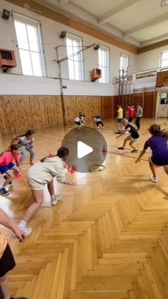 a group of people in a gym playing with frisbees on a hard wood floor