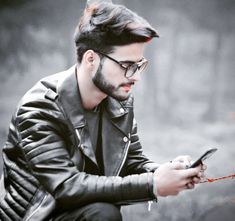 a man with glasses is looking at his cell phone