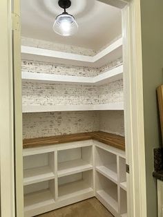 an empty walk in closet with white shelving and wood flooring on the walls