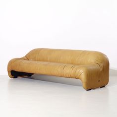 a yellow leather couch sitting on top of a white floor next to a wooden table