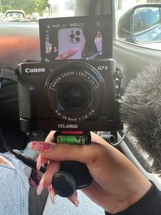 a person is holding up a camera in the back seat of a car while someone takes a photo