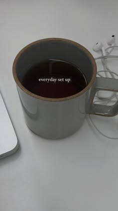 there is a cup of coffee and headphones on the table next to an apple computer