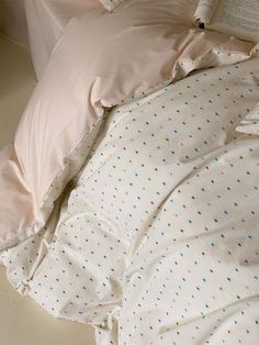 an unmade bed with polka dot sheets and pillows