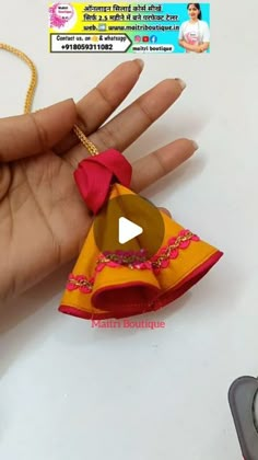 a hand holding a small yellow and red origami doll